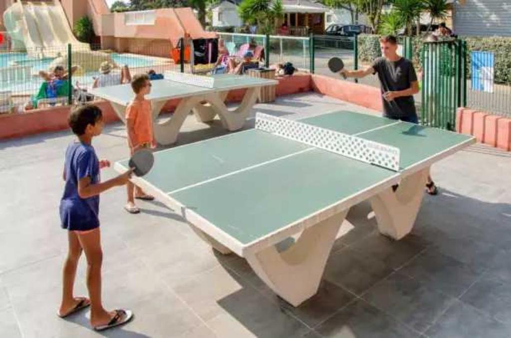 2 enfants jouent au ping-pong sur une table de ping-pong dans l'établissement Appartement 4 étoiles - Parc aquatique - ccaa0ai, à Bormes-les-Mimosas