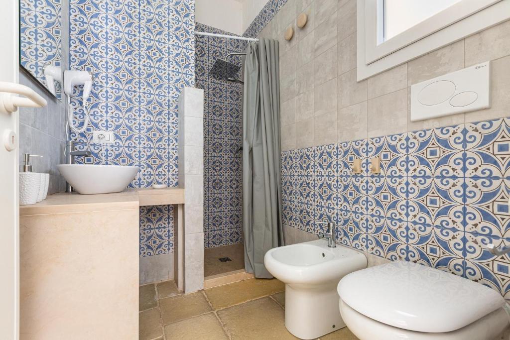 La salle de bains bleue et blanche est pourvue de toilettes et d'une douche. dans l'établissement Villa Elena Nina by BarbarHouse, à Torre Lapillo