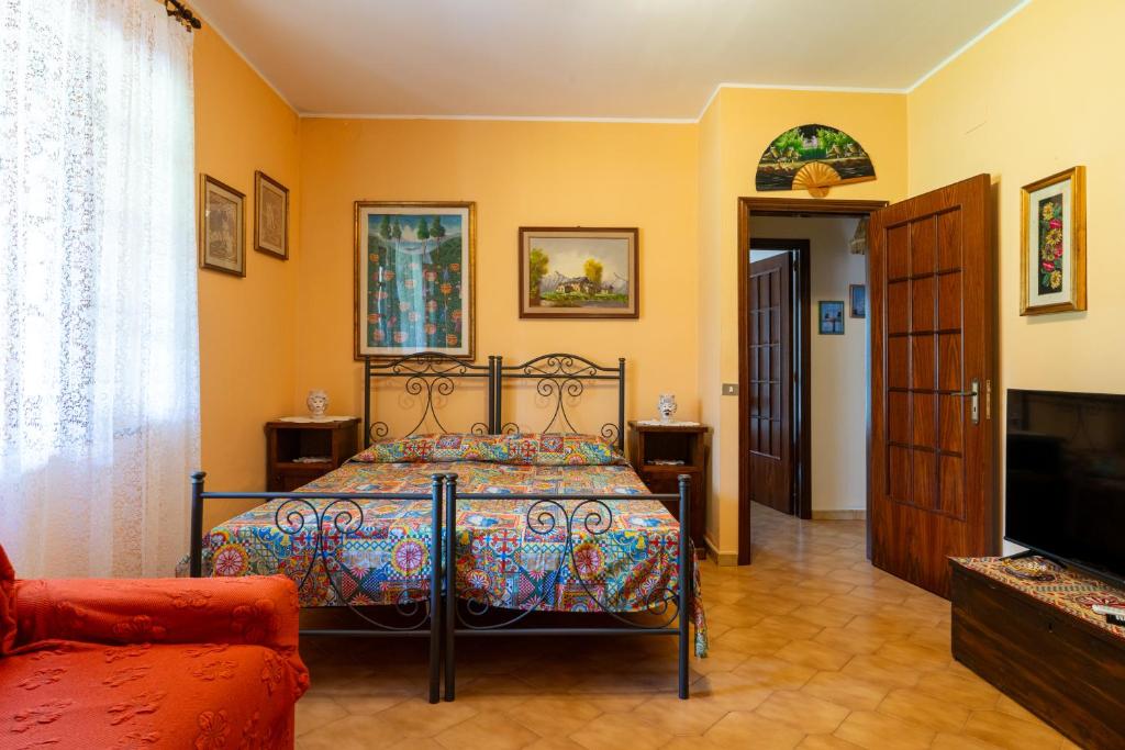 une chambre avec un lit, un canapé et une télévision dans l'établissement Villa in campagna con piscina, à San Fratello