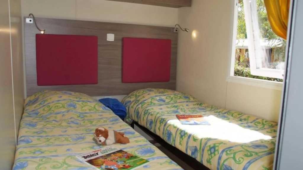 - une chambre avec 2 lits et un animal rembourré sur le lit dans l'établissement Camping 4 étoiles - Parc aquatique - eec0ef, à Agay