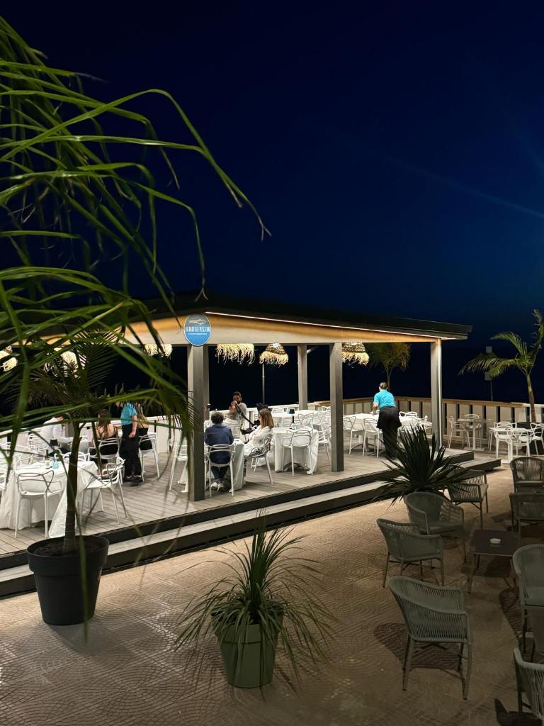 un groupe de personnes assises sur un patio la nuit dans l'établissement Paguro Beach Hotel, à Siculiana Marina