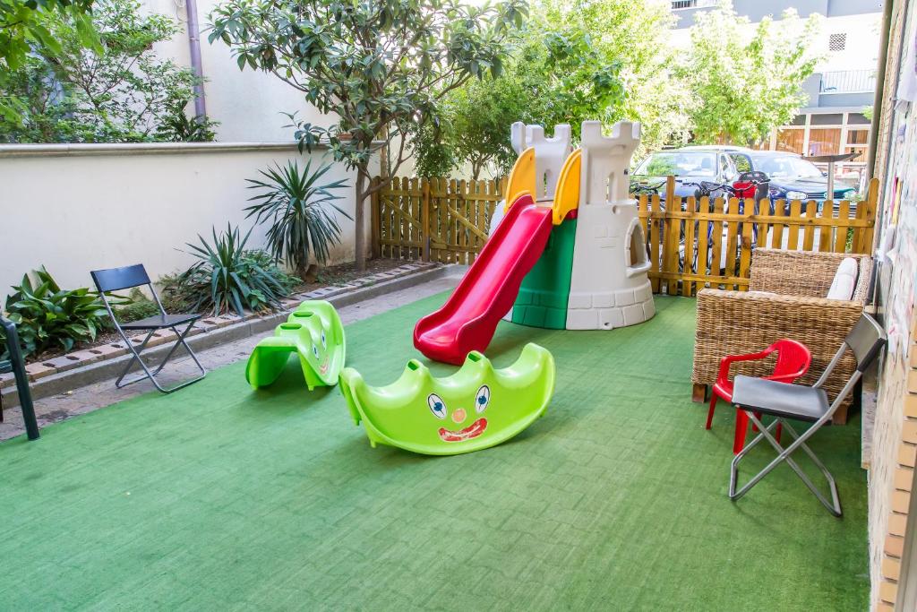 une aire de jeux avec toboggan et chaises sur une pelouse dans l'établissement Hotel Consul - Family Hotel, à Riccione