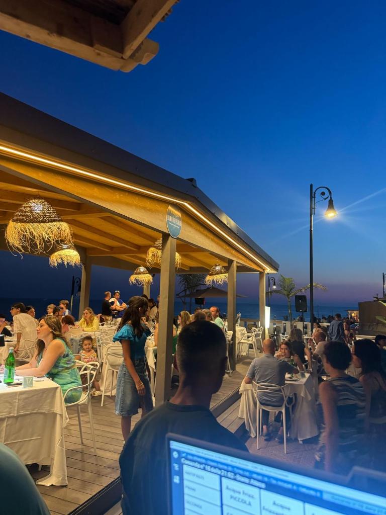 un groupe de personnes assises sur une terrasse dans un restaurant dans l'établissement Paguro Beach Hotel, à Siculiana Marina
