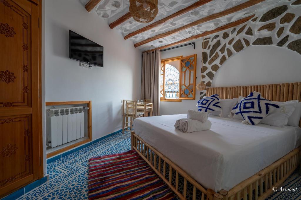 une chambre avec un grand lit dans une pièce dans l'établissement Riad ALHAMBRA, à Chefchaouen
