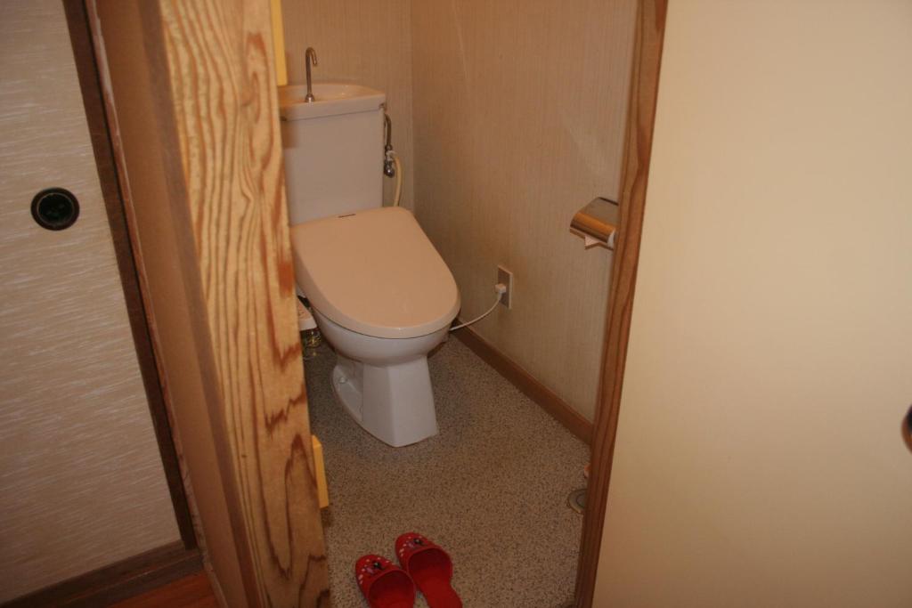 La salle de bains est pourvue de toilettes et d'une paire de chaussures rouges. dans l'établissement Suehirokan, à Tagami