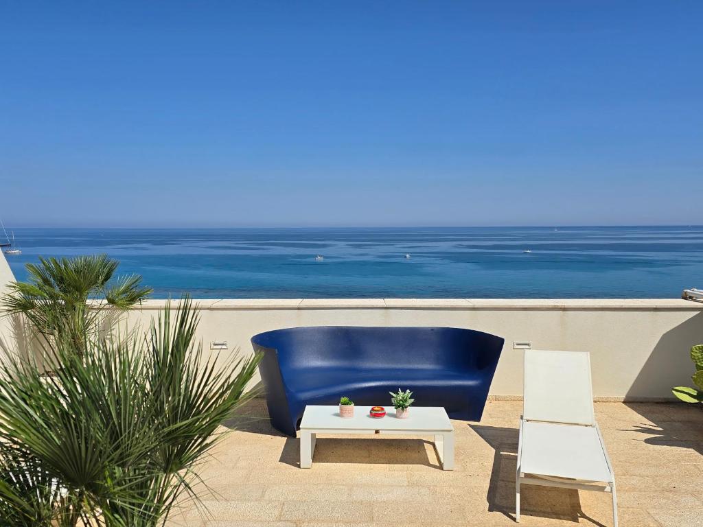 une chaise bleue et une table basse blanche et l'océan dans l'établissement Central Gallery Rooms- Palazzo D'Ali' Staiti XIX, à Trapani