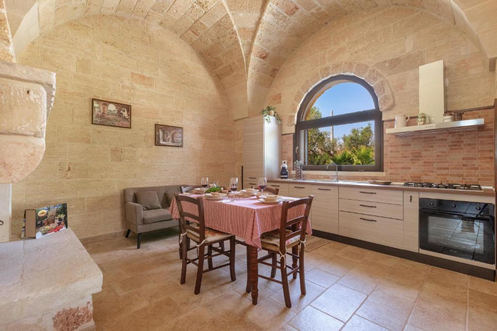 une cuisine et une salle à manger avec une table et une fenêtre dans l'établissement Villa Saracino by Perle di Puglia, à Supersano