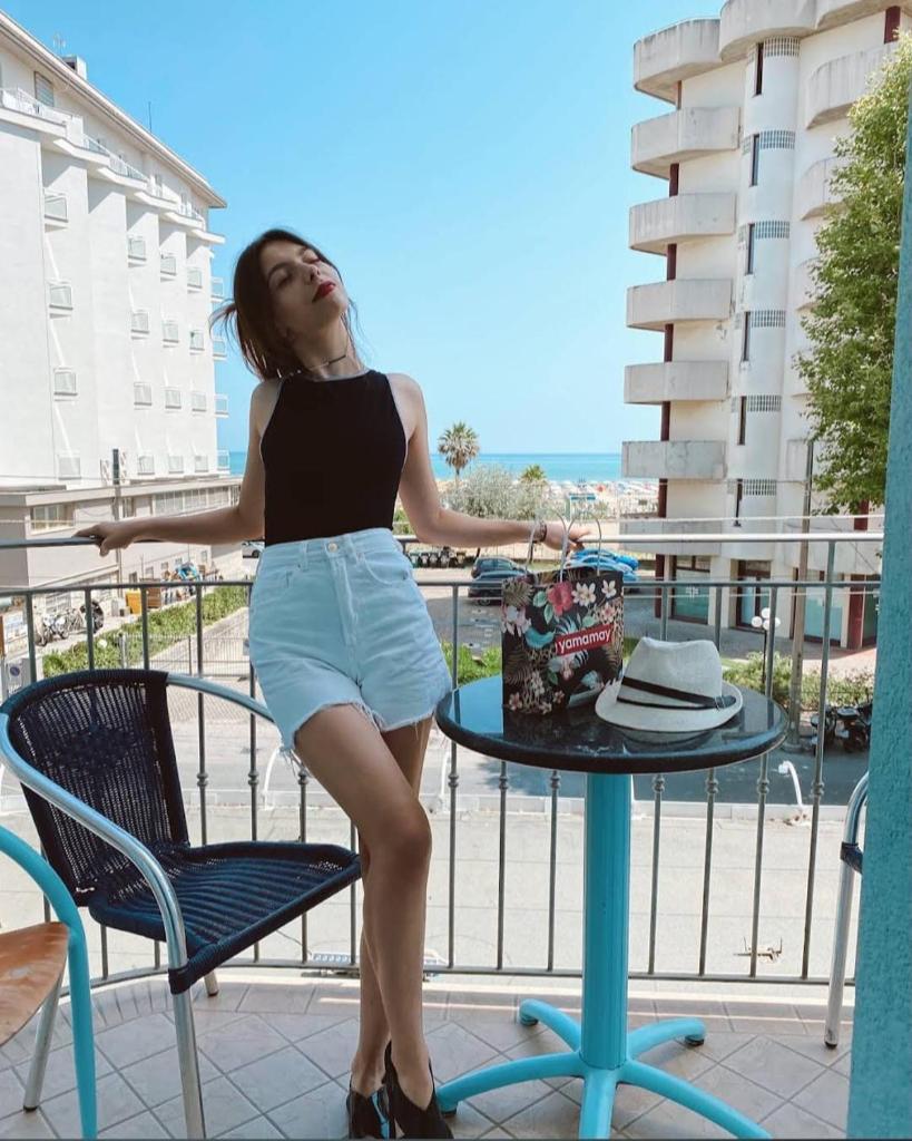 une femme debout à côté d'une table avec un chapeau dans l'établissement Hotel Blue Moon B&B, à Rimini