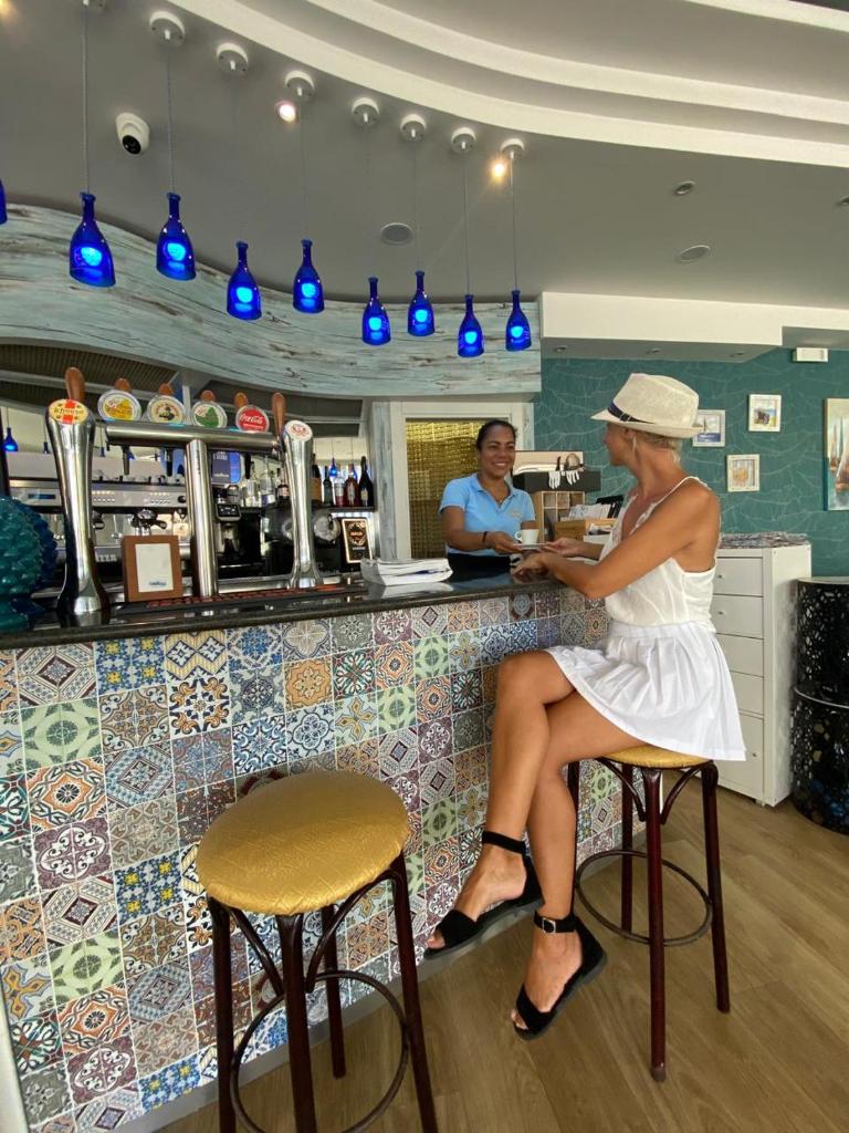 une femme assise au comptoir d'un bar dans l'établissement Hotel Blue Moon B&B, à Rimini