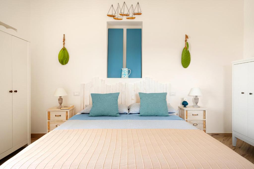 une chambre blanche avec un grand lit avec des oreillers bleus dans l'établissement Le dimore di Ines - con piscina, à Locorotondo
