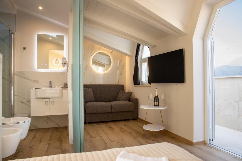 une salle de bain avec un canapé et une télévision dans une chambre dans l'établissement Junior Suite Hotel Biagi, à Lido di Camaiore