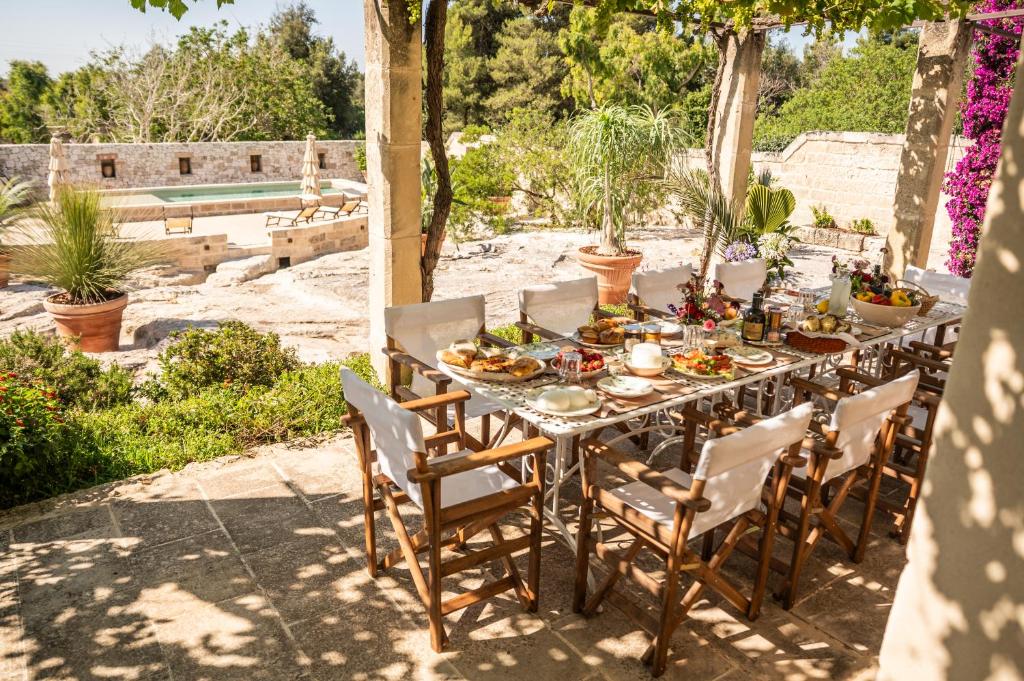 - une grande table avec des chaises et de la nourriture dans l'établissement Masseria Torre Ruggeri, à Carpignano Salentino