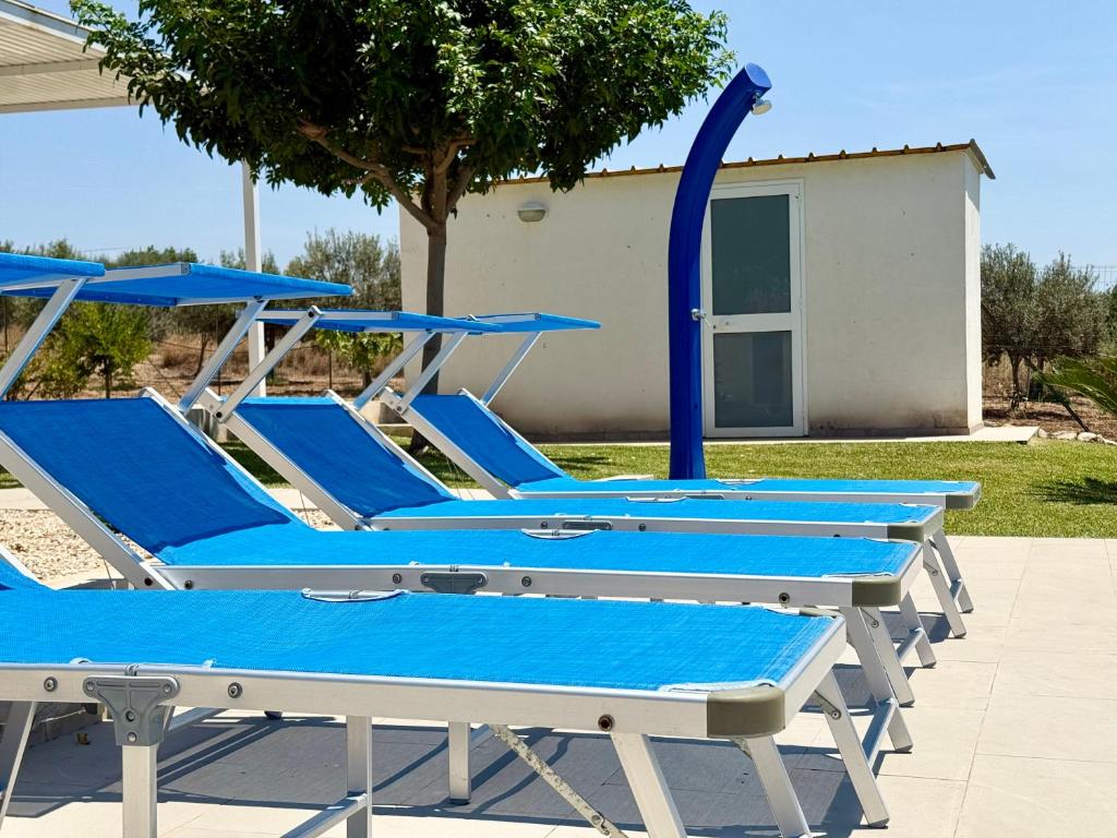 une rangée de chaises longues bleues assises à côté d'un bâtiment dans l'établissement Villa Sema - Marina di Ragusa, à Marina di Ragusa