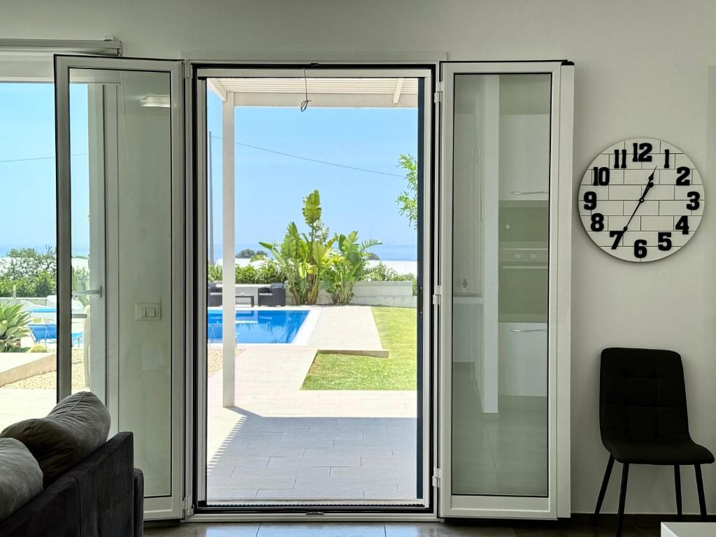 une horloge sur une paroi à côté d'une porte coulissante en verre dans l'établissement Villa Sema - Marina di Ragusa, à Marina di Ragusa
