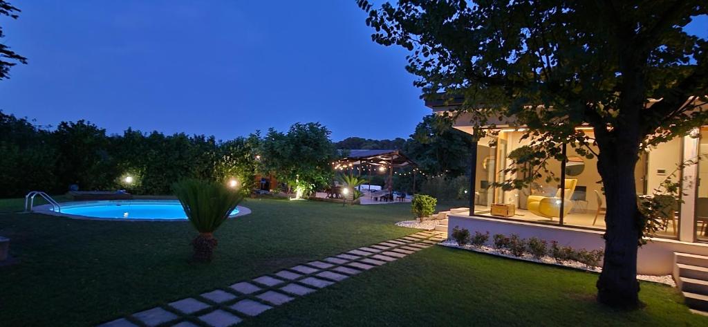 une arrière-cour d'une maison avec une piscine la nuit dans l'établissement ALFA COUNTRY HOUSE Villa Salento, à Lequile