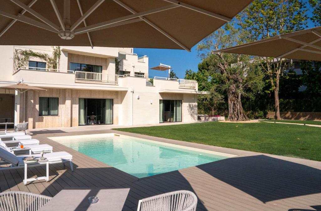 une piscine avec des chaises et un parasol devant un bâtiment dans l'établissement Villa Verdeoro, à Montesilvano