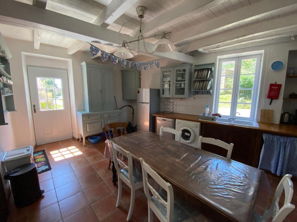 une cuisine avec une table et des chaises dans une pièce dans l'établissement Le Gîte au Coin des Abeilles, à La Caillère