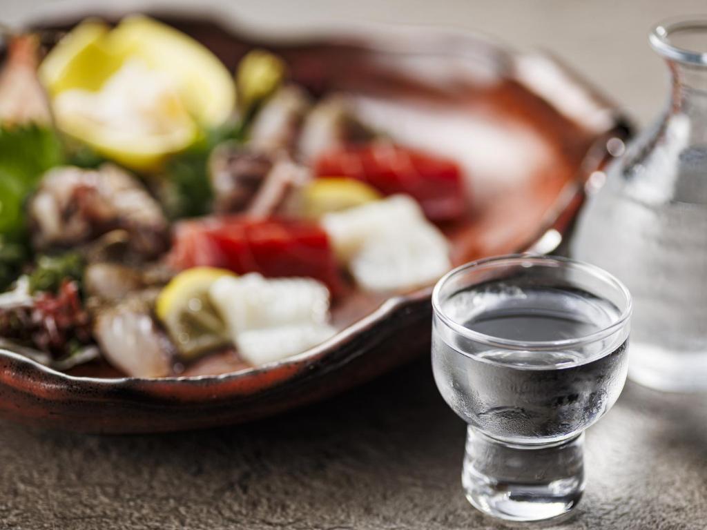 un verre d'eau à côté d'une casserole de nourriture dans l'établissement KAMENOI HOTEL Atami Annex, à Atami