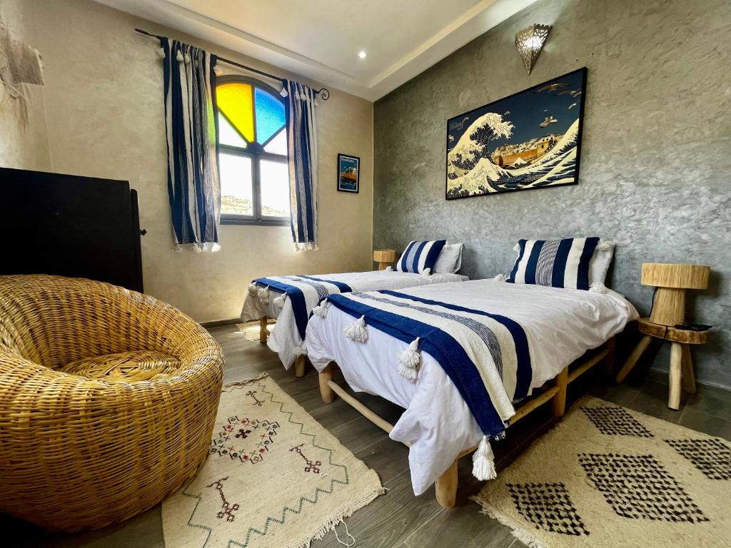 une chambre avec deux lits et une chaise et une fenêtre dans l'établissement Riad La Tempérance, à Essaouira
