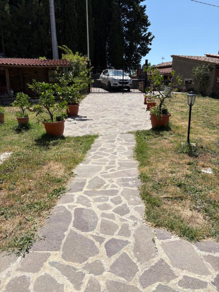 une passerelle en pierre avec des plantes en pot dans une cour dans l'établissement Villa Collina, à Sorano