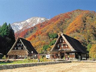 une grande maison avec une montagne en arrière-plan dans l'établissement Gokayama Onsen Akaokan, à Nanto