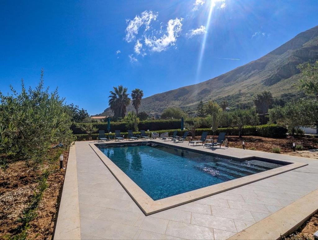 une piscine avec des chaises et des montagnes en arrière-plan dans l'établissement Villa Betta Cuntrariusa con piscina privata e jacuzzi a Scopello, à Castellammare del Golfo