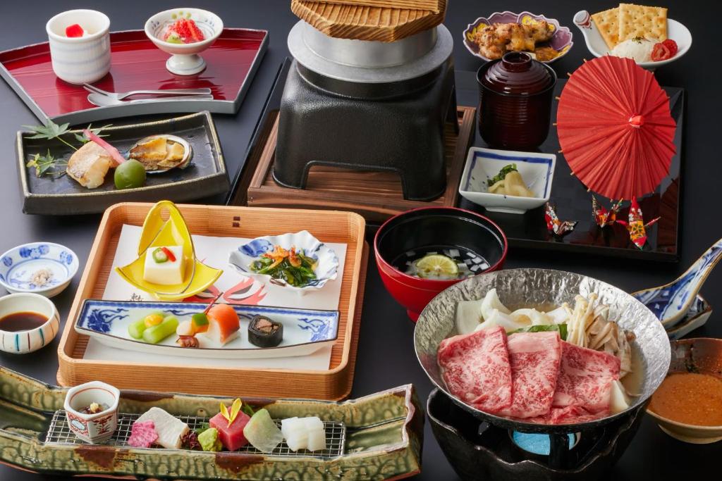 une table recouverte de assiettes et de bols de nourriture dans l'établissement Onyado Shikishima-kan, à Kotohira