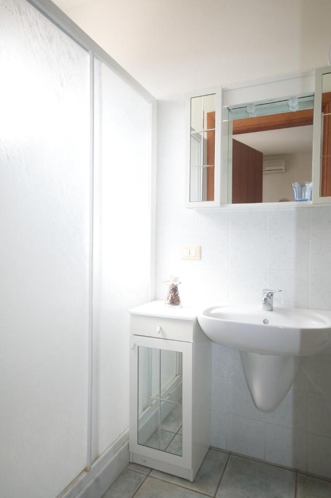 une salle de bain blanche avec un lavabo et un miroir dans l'établissement Residence Loggetta Margherita, à San Vincenzo