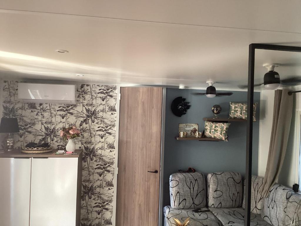 un salon avec une chaise et un miroir dans l'établissement Frejus tout confort, climatisation,plus ventilation toutes les chambres, linge de lit et de toilette , coffre fort, lavé vaisselle machine à laver grande terrasse couverte velos et wifi possible, à Fréjus