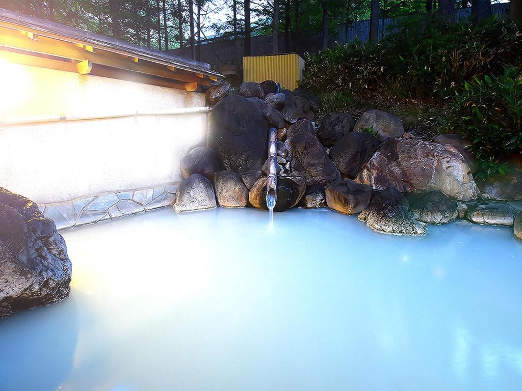une fontaine à eau dans une cour avec des rochers et de l'eau bleue dans l'établissement Okunikko Konishi Hotel, à Nikkō