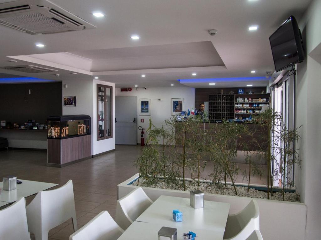 un restaurant avec des tables blanches et des chaises blanches dans l'établissement Hotel Poseidon, à Corigliano Calabro