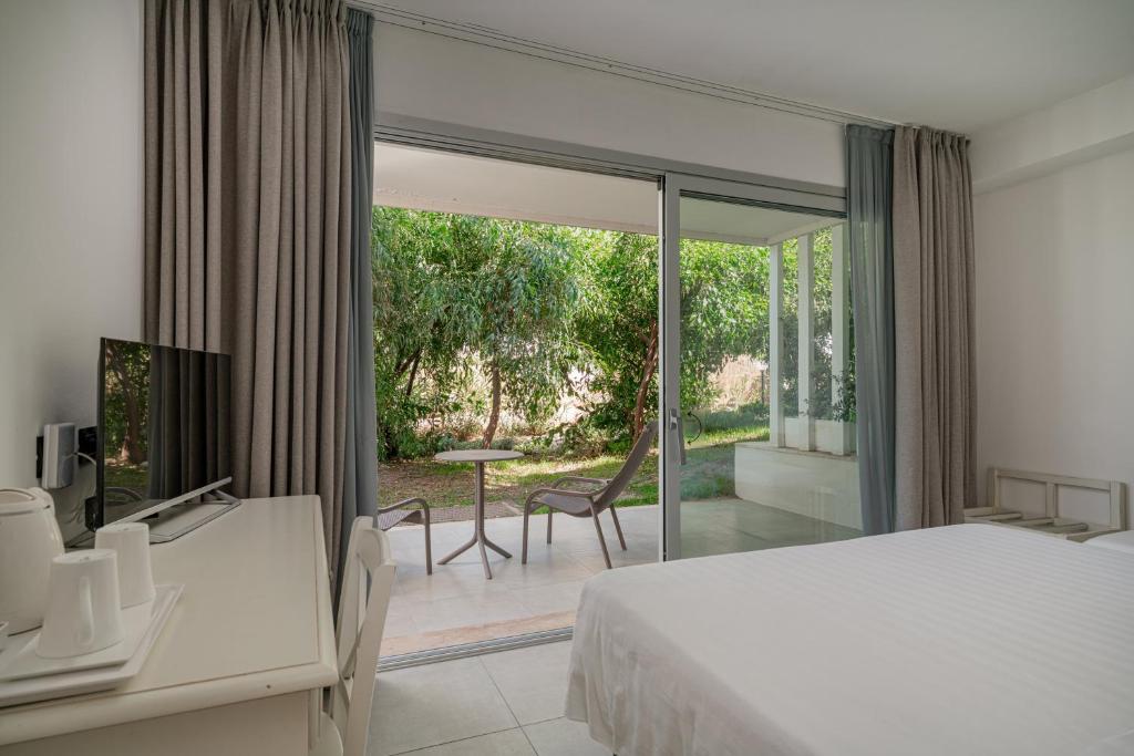 une chambre avec un lit et une porte coulissante en verre dans l'établissement Bellevue Sardinia Resort Affiliated by Meliá, à Valledoria