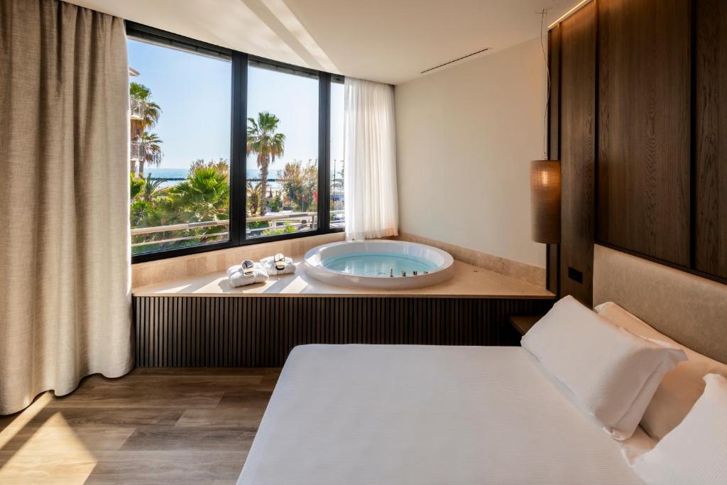 une salle de bain avec une baignoire, un lit et une fenêtre dans l'établissement International Hotel & Suite - In prima fila sul lungomare, à San Benedetto del Tronto