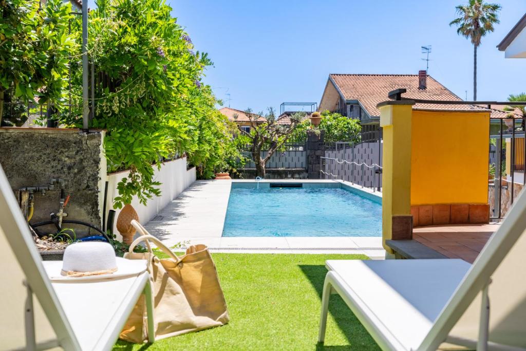 - une piscine dans une cour avec 2 chaises longues dans l'établissement Villa Cesare, à Mascali