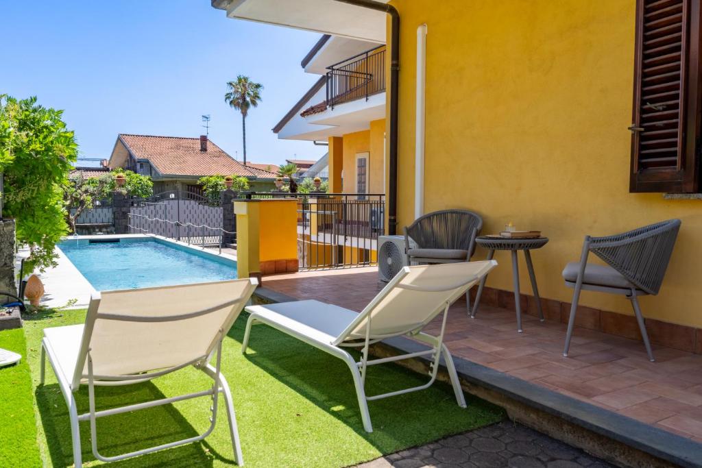 une terrasse avec des chaises, une table et une piscine dans l'établissement Villa Cesare, à Mascali