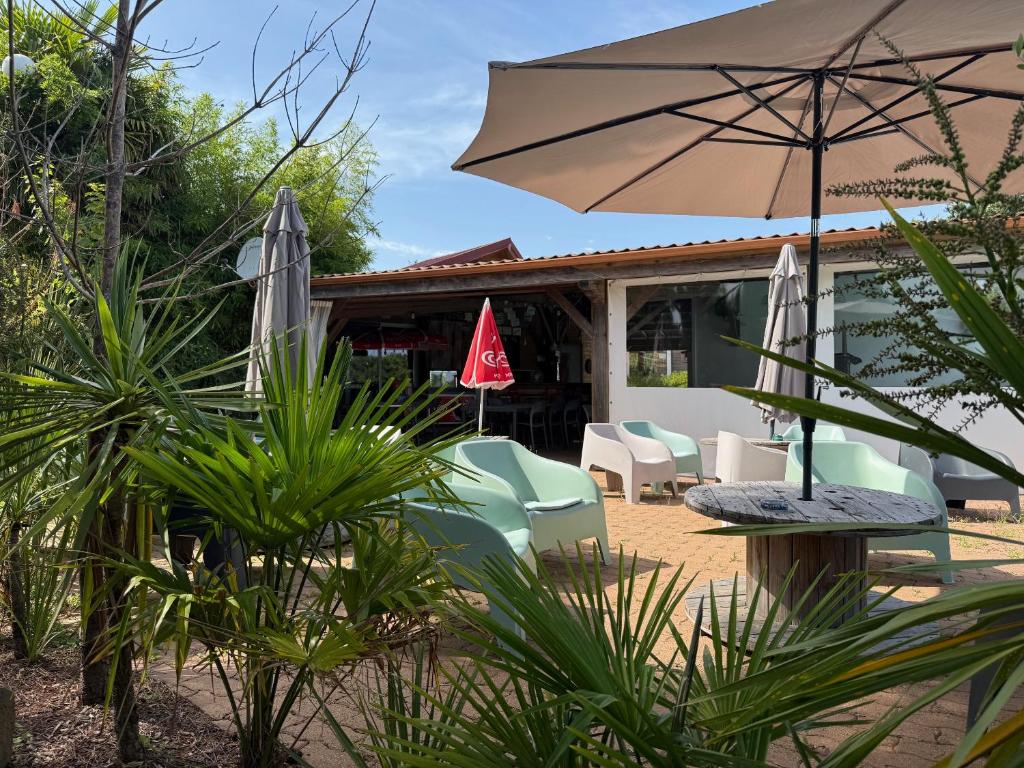 un patio avec une table, des chaises et un parasol dans l'établissement Le domaine de la billardière, à Moutiers-les-Mauxfaits