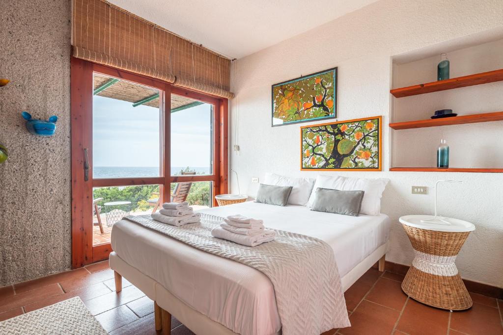 une chambre avec un lit et une grande fenêtre dans l'établissement Pedra - Seaside & pool villa in wild Mediterranean, à San Stèfano