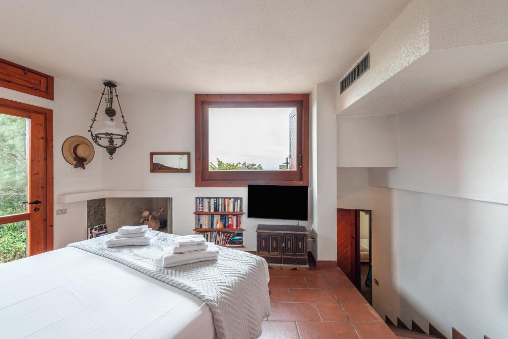 une chambre avec un lit blanc et une télévision dans l'établissement Pedra - Seaside & pool villa in wild Mediterranean, à San Stèfano