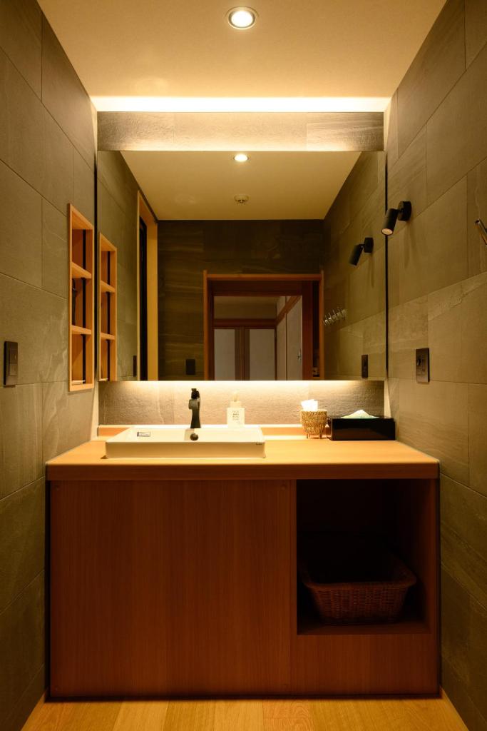 une salle de bain avec un lavabo et un grand miroir dans l'établissement Suminoyu, à Yamanouchi
