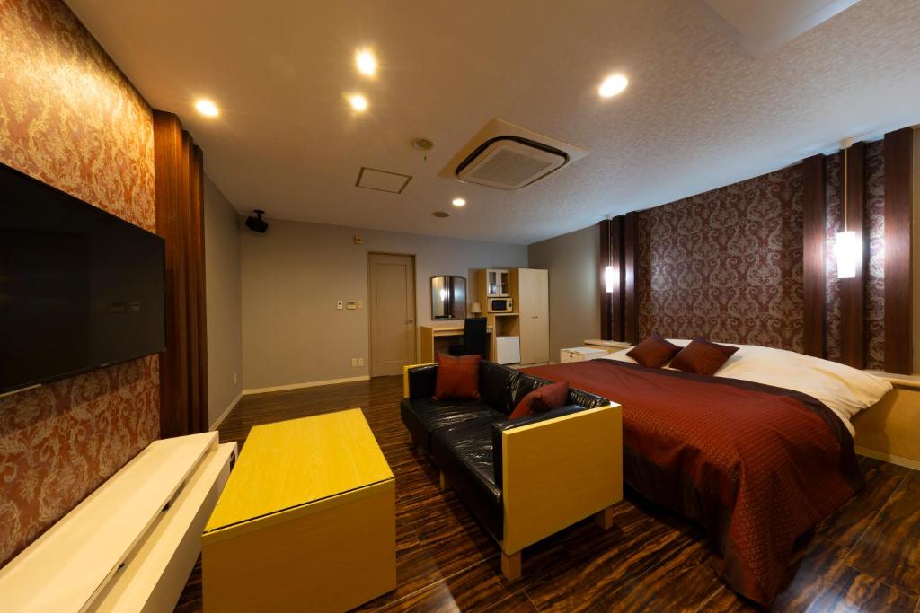 une chambre avec un lit, un canapé et une télévision dans l'établissement パサディナホテル11 市原店, à Ichihara