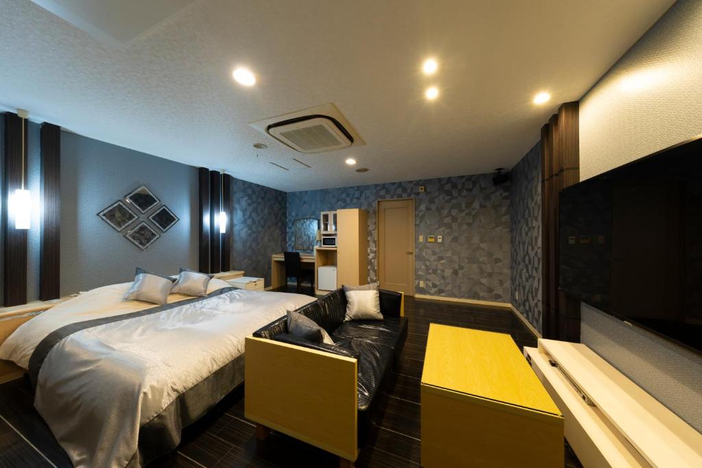 une chambre avec un grand lit et un canapé dans l'établissement パサディナホテル11 市原店, à Ichihara