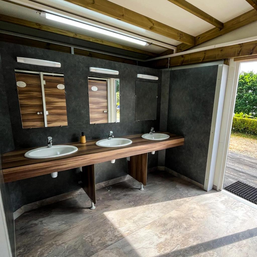 une salle de bain avec deux lavabos et deux miroirs dans l'établissement Lodg'ing Nature Camp Presqu'île Crozon, à Lanvéoc