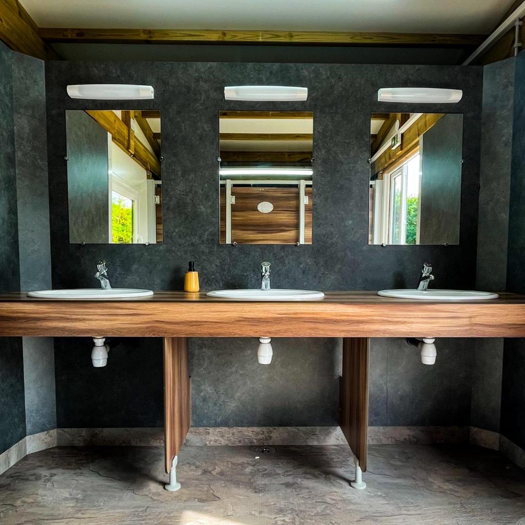 une salle de bain avec deux lavabos et deux miroirs dans l'établissement Lodg'ing Nature Camp Presqu'île Crozon, à Lanvéoc