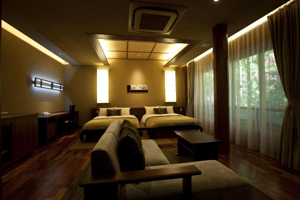 une chambre d'hôtel avec deux lits et un canapé dans l'établissement TAKITEI Riverside Onsen ーA Hidden Ryokan in Kanazawaー, à Kanazawa