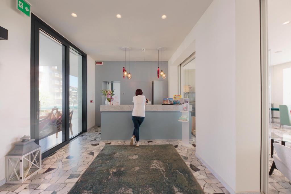 une personne debout à un comptoir dans une cuisine dans l'établissement Hotel Ariston, à Caorle 62 autres photos