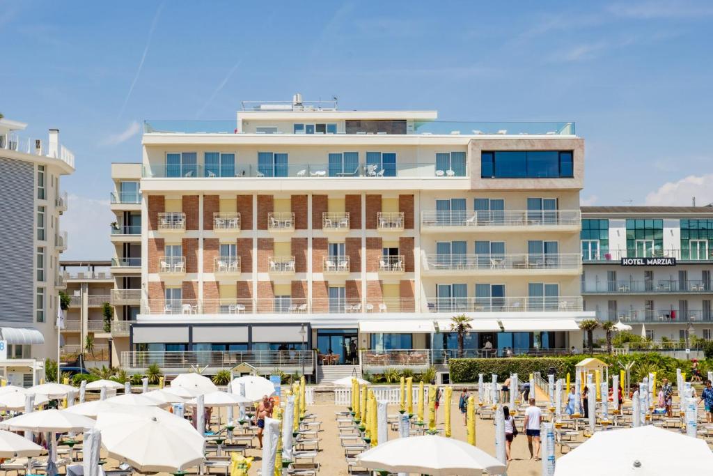 un hôtel avec des chaises et des parasols sur la plage dans l'établissement Hotel Ariston, à Caorle