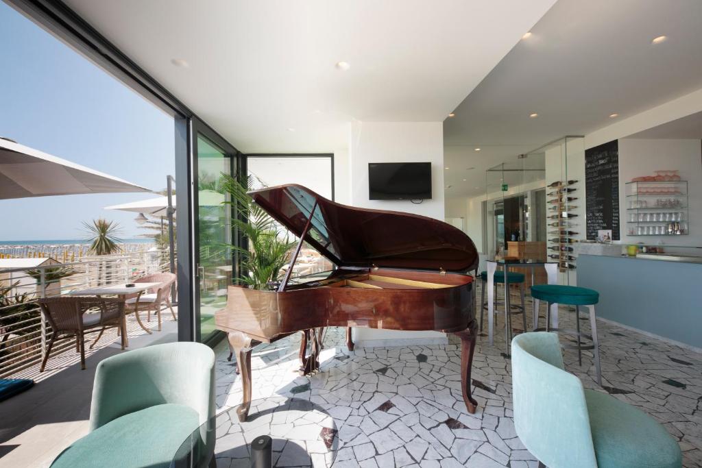 - un piano dans une pièce avec des chaises et une table dans l'établissement Hotel Ariston, à Caorle