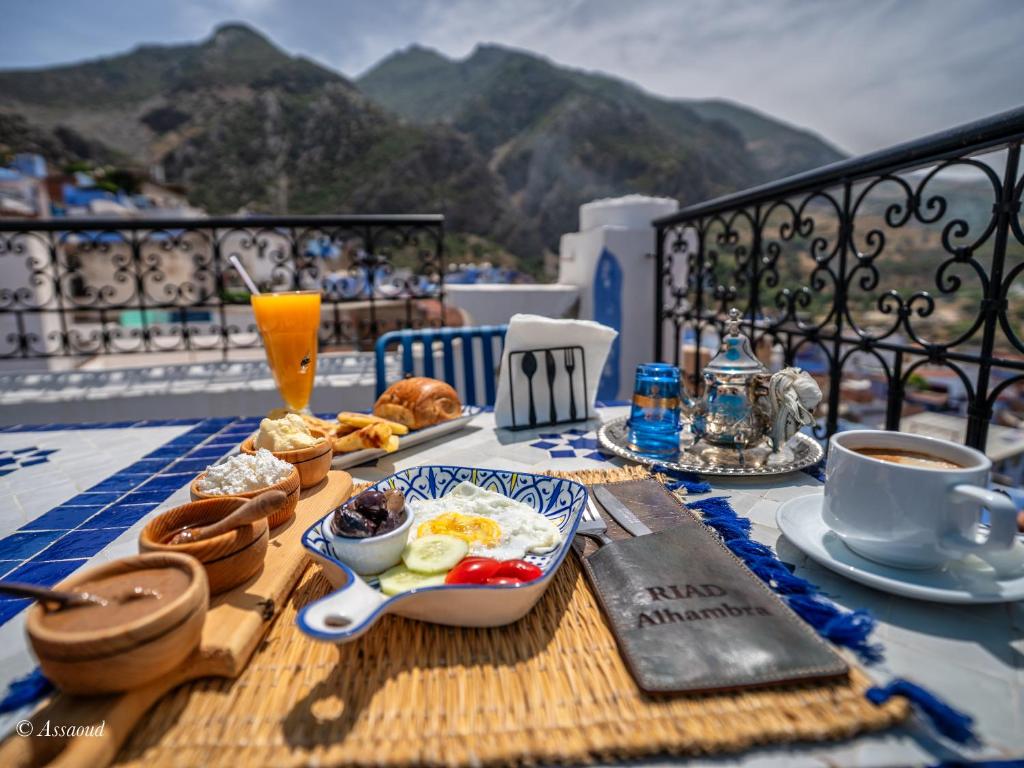 - une table de petit-déjeuner avec des aliments pour le petit-déjeuner et du café sur le balcon dans l'établissement Riad ALHAMBRA, à Chefchaouen