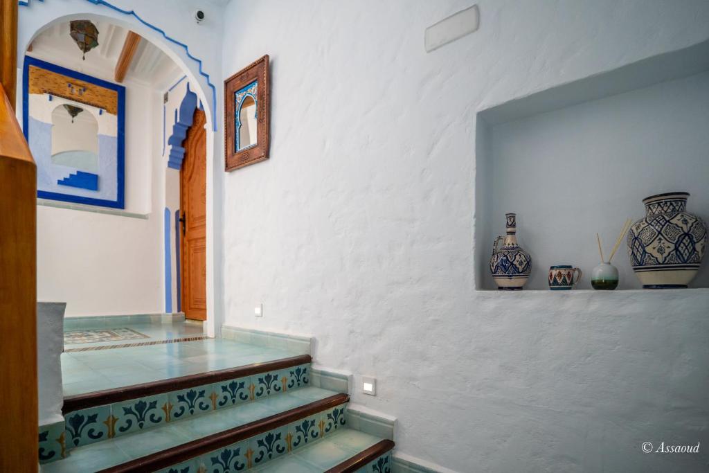 un couloir avec des vases au mur et un escalier dans l'établissement Riad ALHAMBRA, à Chefchaouen