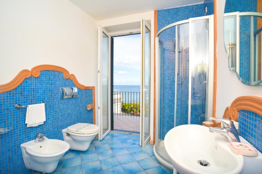 La salle de bains est pourvue de carrelage bleu, de toilettes et d'un lavabo. dans l'établissement Albergo Italia - Beach Hotel, à Ischia